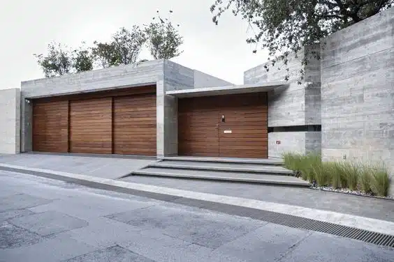 fachada de casa com Estruturas alinhadas de concreto e portão de madeira